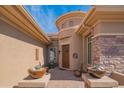 Covered entryway with stone accents, desert landscaping, and a decorative wood door with sidelight windows at 40607 N Candlewyck Ln, Phoenix, AZ 85086