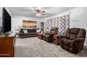 Cozy living room with plush seating, soft carpet, and a decorative ceiling fan at 5256 W Port Au Prince Ln, Glendale, AZ 85306