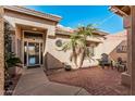 Inviting front courtyard with stone pavers, mature palm trees, a seating area, and a decorative glass front door at 5902 S Amberwood Dr, Sun Lakes, AZ 85248