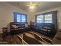 Cozy living room featuring a dark brown leather sofa, wood flooring, and ample natural light from the windows at 650 N Hawes Rd # 3827, Mesa, AZ 85207