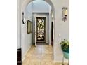 Inviting entryway with decorative front door, sconce lighting, neutral tile flooring, and arched doorway at 17012 S 27Th Ln, Phoenix, AZ 85045