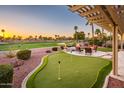 Covered patio with fire bowls, putting green, waterfall feature, seating area and golf course in the background at 22020 N San Ramon Dr, Sun City West, AZ 85375