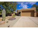 Charming stucco home with a two-car garage, desert landscaping and a concrete driveway at 9576 E Kiisa Dr, Scottsdale, AZ 85262