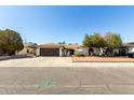 A single-story home featuring a two-car garage, desert landscaping and mature trees at 10008 N 50Th Dr, Glendale, AZ 85302