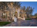 Elegant house showcasing an impressive entryway with an arched doorway and a lush, green lawn at 20715 N 103Rd Pl, Scottsdale, AZ 85255