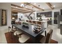 Open concept living and dining area, wood beam ceilings, and a modern kitchen island with bar seating at 3307 W Storm Cloud St, San Tan Valley, AZ 85144
