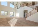 Spacious living room featuring large windows, a ceiling fan, staircase, and carpeted floors at 44440 W Palmen Dr, Maricopa, AZ 85138