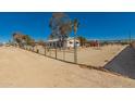 A fenced desert property featuring an open yard with trees against a bright blue sky at 1015 N 193Rd Ave, Buckeye, AZ 85326