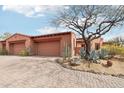 Desert home featuring a three-car garage, complemented by drought-resistant landscaping and a paved driveway at 12160 E Whispering Wind Dr, Scottsdale, AZ 85255