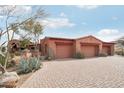 Charming desert home with a spacious three-car garage, brick driveway, and beautiful xeriscaping at 12160 E Whispering Wind Dr, Scottsdale, AZ 85255