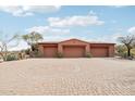 Spacious three-car garage with brick driveway and lush desert landscaping, adding curb appeal to the property at 12160 E Whispering Wind Dr, Scottsdale, AZ 85255