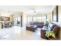 Bright living room featuring white tile floors, comfortable leather sofas, and access to the dining area at 16416 W Rock Springs Ln, Surprise, AZ 85374