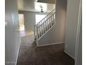 Bright entryway with a staircase leading to the upper level, featuring neutral carpeting at 17345 N Costa Brava Ave, Maricopa, AZ 85139