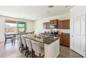 Modern kitchen with an oversized island, stylish seating, stainless steel appliances, and wood cabinets at 23689 W Watkins St, Buckeye, AZ 85326