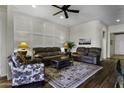 Inviting living room with a decorative accent wall, plush seating, ceiling fan, and wood-look floors at 40830 W Bedford Dr, Maricopa, AZ 85138