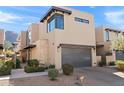 Modern home exterior with a gray garage door, stone accents, desert landscaping, and mountain views at 5541 E Stella Ln, Paradise Valley, AZ 85253