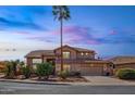 Charming two-story home with a desert landscape, palm tree, and tile roof at dusk at 6105 W Kimberly Way, Glendale, AZ 85308