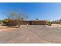 Tan single-story home with a spacious driveway and tree in the front yard at 7102 E Larkspur Dr, Scottsdale, AZ 85254