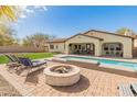 Spacious backyard with a pool, patio, fire pit, and ample seating for outdoor entertaining and relaxation at 30259 N 125Th Ln, Peoria, AZ 85383