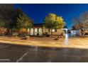 Inviting single-story home with a well-manicured front yard and charming facade at twilight at 30259 N 125Th Ln, Peoria, AZ 85383