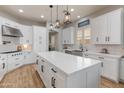 Modern kitchen with a large island, white cabinets, stainless steel appliances, and designer lighting fixtures at 30259 N 125Th Ln, Peoria, AZ 85383