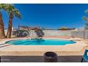 Backyard pool is surrounded by concrete and rock, with a diving board and privacy wall at 4154 W Grovers Ave, Glendale, AZ 85308