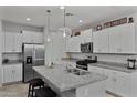 Well-lit kitchen with stainless steel appliances, granite countertops, and a spacious island with barstools at 42195 W Lavender Dr, Maricopa, AZ 85138