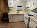 Functional kitchen with a gas range, cream cabinetry, and a window unit for cooling and ventilation at 9501 E Broadway Rd # 71, Mesa, AZ 85208