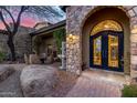 Close up of an elegant arched entryway with a custom iron front door and decorative stone archway at 10638 E Hedgehog Pl, Scottsdale, AZ 85262