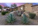 An exterior shot of the home showcasing desert landscaping with large rocks and native plants at 10638 E Hedgehog Pl, Scottsdale, AZ 85262