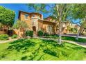 Charming two-story home with a stone turret, arched entry, green lawn, and mature landscaping at 1152 W Horseshoe Ave, Gilbert, AZ 85233