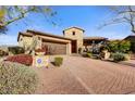 Charming single-story home with a stone facade, manicured landscaping, and a paver driveway leading to a two-car garage at 17991 N 95Th St, Scottsdale, AZ 85255