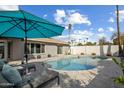 Inviting backyard pool area featuring a pool with lounge chairs, a large umbrella, and well-maintained landscaping at 2256 S Noche De Paz --, Mesa, AZ 85202