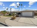 Charming single-story home featuring desert landscaping, tall palm trees, a two-car garage, and an arched entryway at 2256 S Noche De Paz --, Mesa, AZ 85202