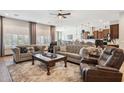 Spacious living room featuring plush sofas, large windows with plantation shutters, and an open floor plan at 26019 W Ponderosa Ln, Buckeye, AZ 85396