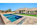 Backyard oasis with a modern pool and spa, travertine decking, and a view of the home's exterior at 8730 E Tether Trl, Scottsdale, AZ 85255