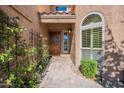 Charming home entryway with a wooden door, stone pathway, decorative sidelight and manicured greenery at 10490 E Dreyfus E Ave, Scottsdale, AZ 85260