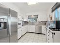 Well-lit kitchen featuring stainless steel appliances, white cabinetry, and tile flooring at 11011 N Coggins Dr, Sun City, AZ 85351