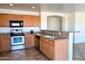 Well-lit kitchen featuring stainless steel appliances, wood cabinets, and granite countertops with backsplash at 1132 S 242Nd Ln, Buckeye, AZ 85326