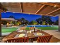 Outdoor dining area under a covered patio, showcasing a view of the pool, lounge area, and manicured lawn at 11801 N Sundown Dr, Scottsdale, AZ 85260
