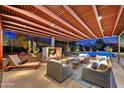 Inviting covered patio with fireplace, lounge seating, and view of the sparkling pool and lush desert landscaping at 11801 N Sundown Dr, Scottsdale, AZ 85260