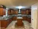 Spacious kitchen with dark wood cabinets, a center island, and stainless steel appliances at 12733 W Boca Raton Rd, El Mirage, AZ 85335