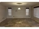 Spacious living room with tile flooring, two windows and a hanging light fixture at 12733 W Boca Raton Rd, El Mirage, AZ 85335