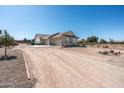 Residential home with a three-car garage and a long gravel driveway leading up to the house at 18637 E Flintlock Dr, Queen Creek, AZ 85142