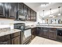Well-equipped kitchen featuring dark cabinets, stainless steel appliances, and a breakfast bar at 18648 W Lupine Ave, Goodyear, AZ 85338