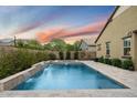 Backyard pool area has travertine tile, flowing water feature, and surrounding green foliage at 4088 E Comstock Dr, Gilbert, AZ 85296