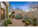 Desert courtyard featuring a mix of drought-tolerant plants, stone accents, a fountain, and desert landscaping at 10767 E Santa Fe Trl, Scottsdale, AZ 85262