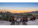 Outdoor seating area with a stone patio, fire pit, and scenic mountain views at sunset at 40947 N 107Th Pl, Scottsdale, AZ 85262