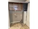 Compact utility room with tiled floors, shelving and a water heater at 6617 W Peck Dr, Glendale, AZ 85301