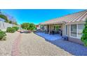 A charming backyard features gravel landscaping, a stone patio, and mature trees at 8444 W Rockwood Dr, Peoria, AZ 85382